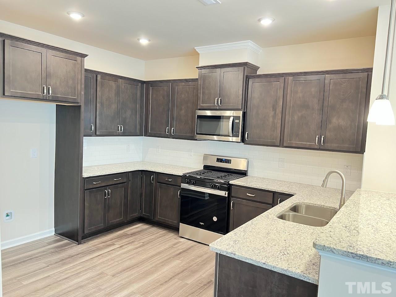 4812 Trikala Avenue Raleigh, NC 27603 - Photo 4 of 16 a kitchen with a sink a stove a refrigerator cabinets and wooden floor