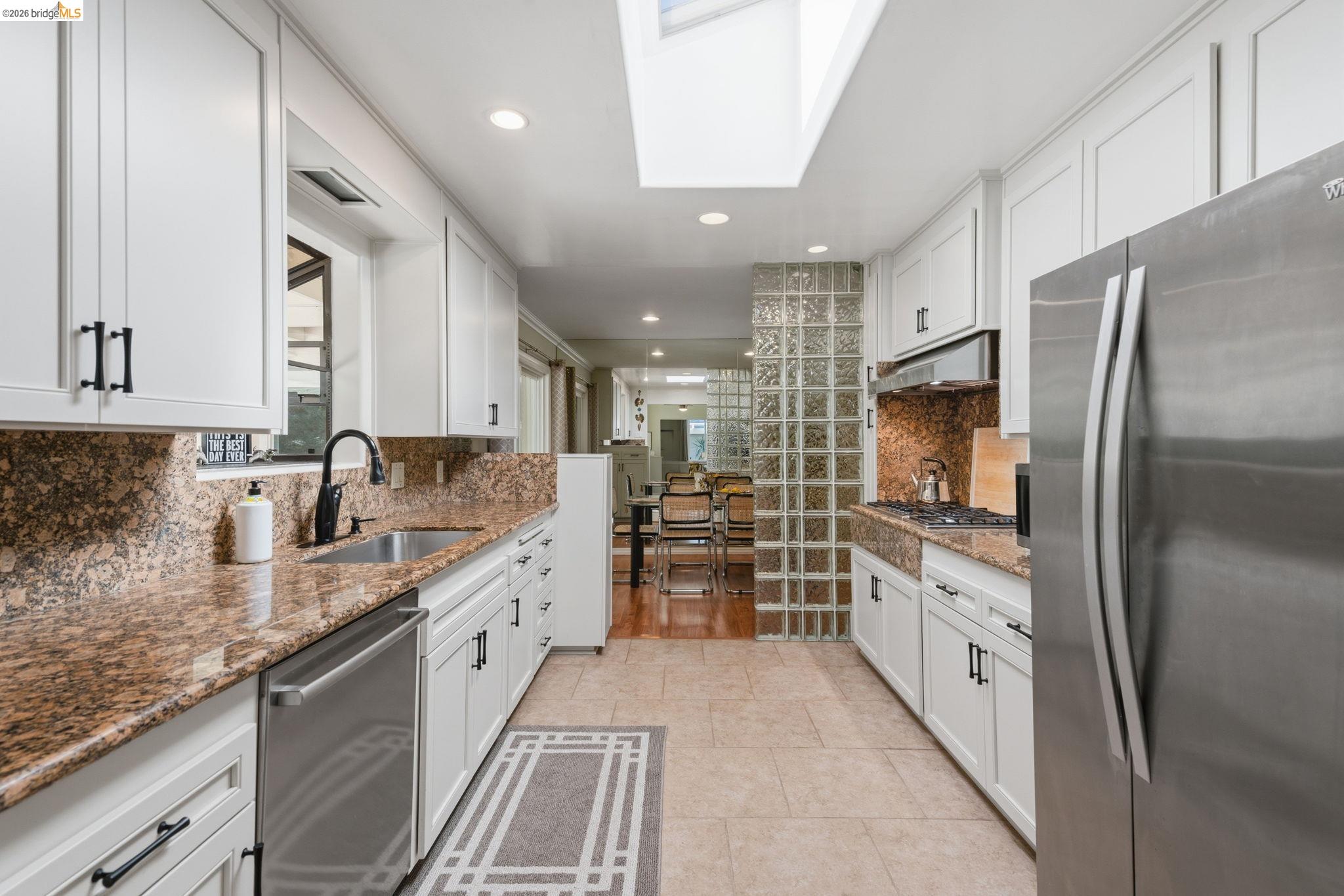 5075 Alhambra Valley Road Martinez, CA 94553 - Photo 13 of 68 Galley kitchen featuring a skylight, recessed lighting, white cabinetry with dark hardware, stone countertops, and stainless steel appliances