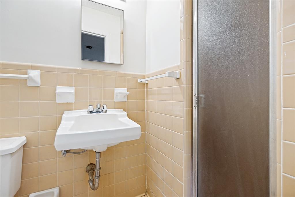5319 Urban Crest Road Dallas, TX 75227 - Photo 18 of 21 Bathroom featuring a wall-mounted sink, chrome faucet, and tiled walls in a neutral tone