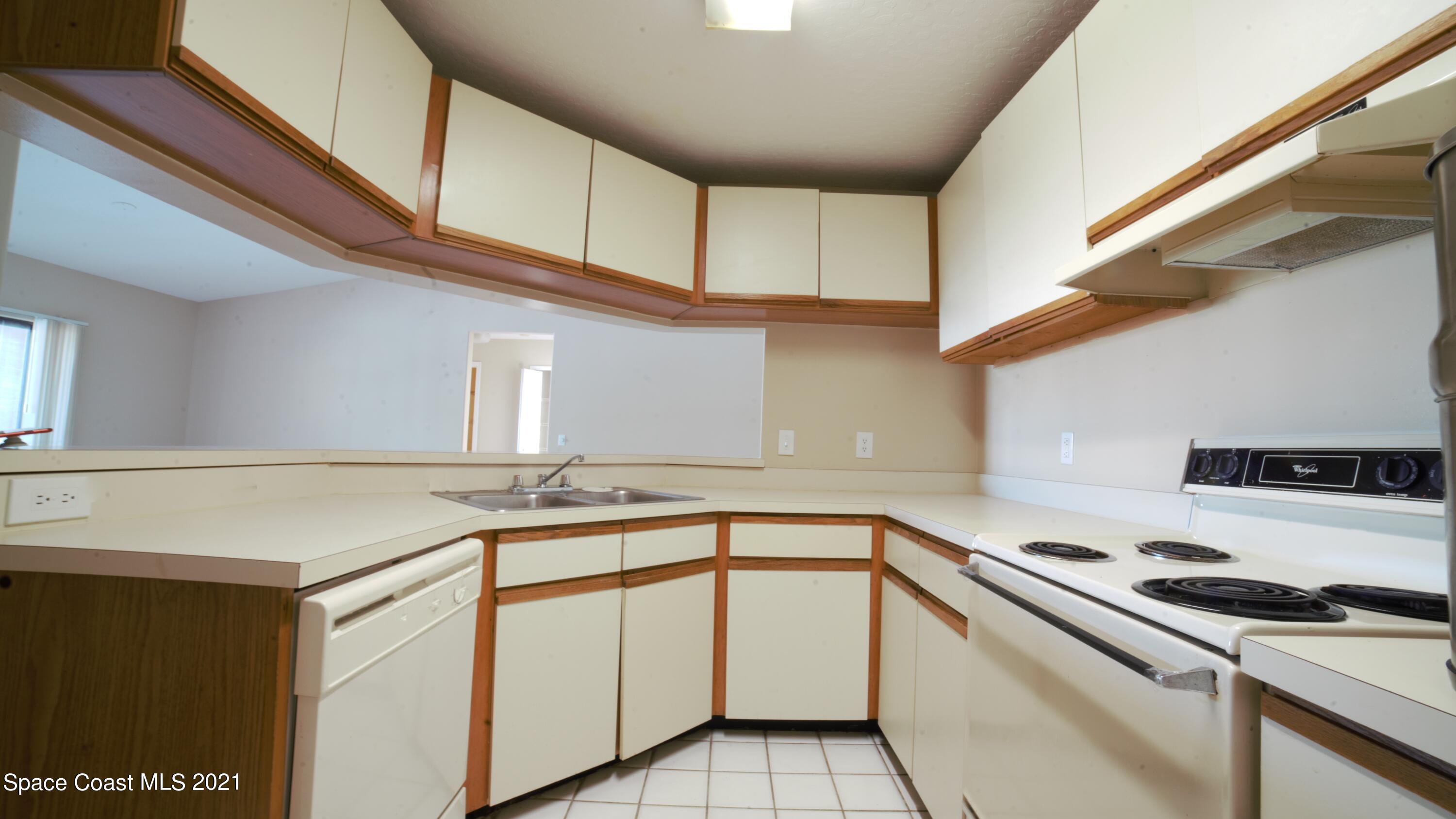 7667 North Wickham Road, Unit 1309 Melbourne, FL 32940 - Photo 7 of 18 a kitchen with granite countertop a sink and white cabinets