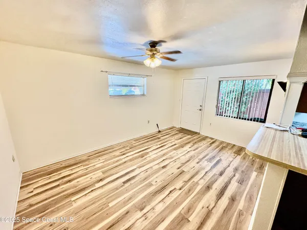 a view of a bedroom with wooden floor and a ceiling fan