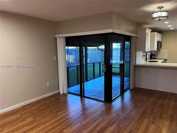 a living room with wooden floors and kitchen view