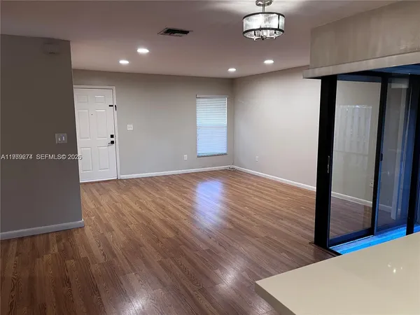 an empty room with wooden floor and chandelier