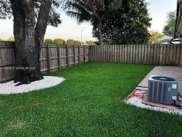 a view of a house with a small yard plants and large tree