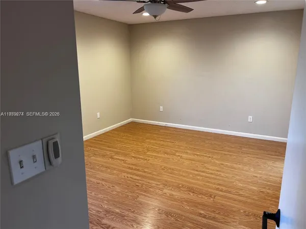 an empty room with a ceiling fan and wooden floor