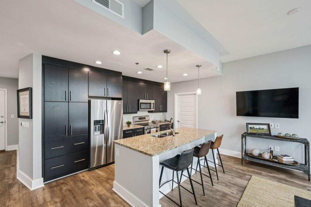 1080 Peachtree Street Northeast, Unit 1012 Atlanta, GA 30309 - Photo 12 of 46 a kitchen with a refrigerator and a flat screen tv