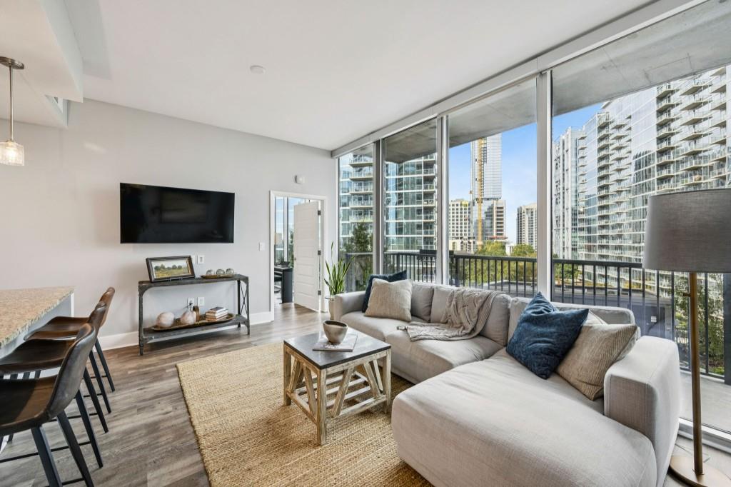 1080 Peachtree Street Northeast, Unit 1012 Atlanta, GA 30309 - Photo 13 of 46 a living room with furniture a flat screen tv and a floor to ceiling window