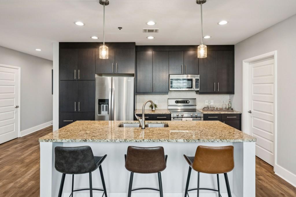 1080 Peachtree Street Northeast, Unit 1012 Atlanta, GA 30309 - Photo 15 of 46 a kitchen with stainless steel appliances granite countertop a refrigerator a stove a sink and a microwave