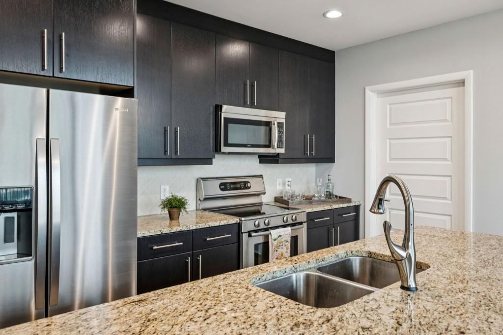 1080 Peachtree Street Northeast, Unit 1012 Atlanta, GA 30309 - Photo 16 of 46 a kitchen with stainless steel appliances granite countertop a refrigerator a sink a stove a microwave and wooden cabinets