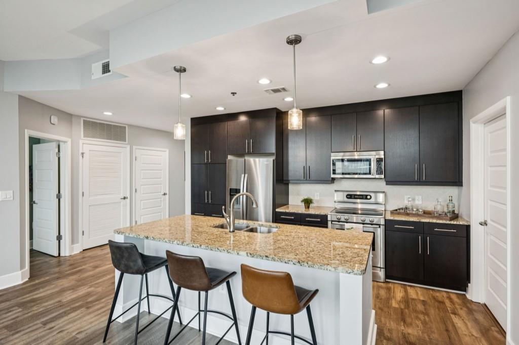 1080 Peachtree Street Northeast, Unit 1012 Atlanta, GA 30309 - Photo 2 of 46 a kitchen with stainless steel appliances kitchen island granite countertop a sink refrigerator and cabinets