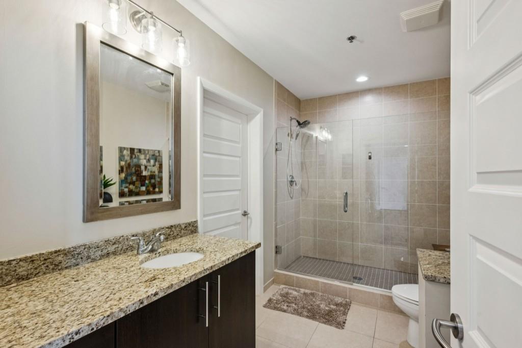 1080 Peachtree Street Northeast, Unit 1012 Atlanta, GA 30309 - Photo 25 of 46 a bathroom with a granite countertop sink a toilet a mirror and shower