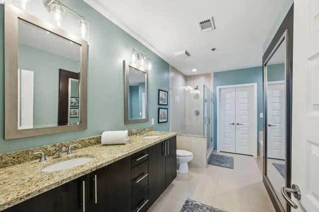 a bathroom with a granite countertop double vanity sink mirror and double