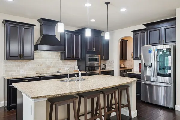 a kitchen with stainless steel appliances granite countertop a sink refrigerator and cabinets
