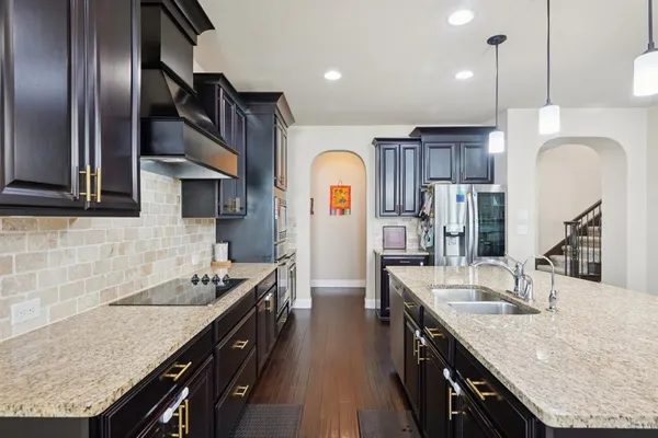 a kitchen with stainless steel appliances granite countertop a sink a stove and a refrigerator