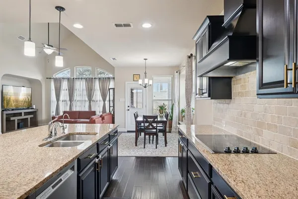 a kitchen with stainless steel appliances granite countertop a sink a stove and a wooden floors