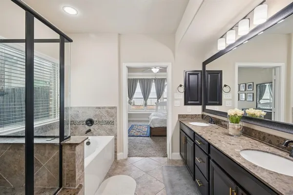 a spacious bathroom with a granite countertop tub sink a mirror and shower
