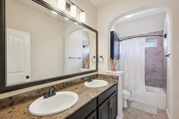 a bathroom with a granite countertop double vanity sink and a mirror