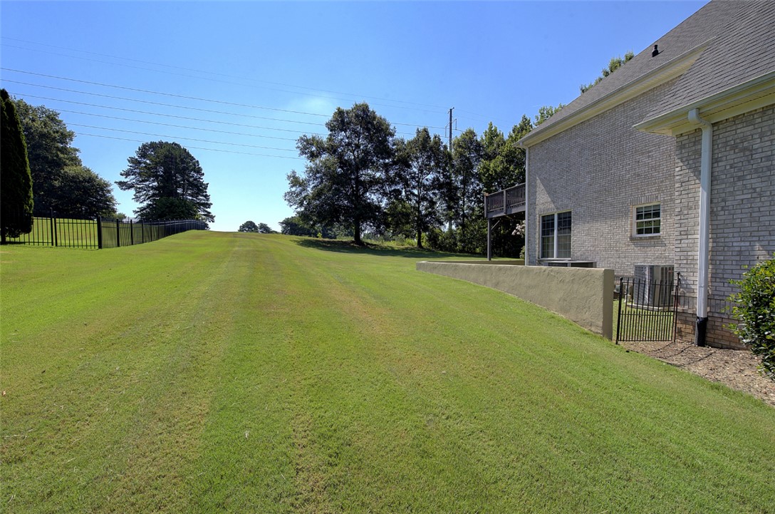 100 Turnberry Road Anderson, SC 29621 - Photo 34 of 41 A spacious backyard with a meticulously maintained lawn, framed by mature trees and a sturdy black fence.