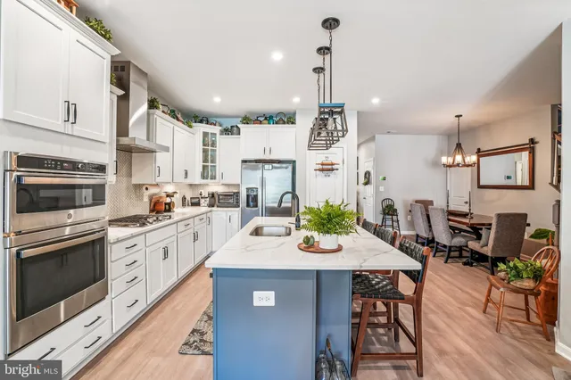 a large kitchen with stainless steel appliances a stove a chimney a sink and a living room view