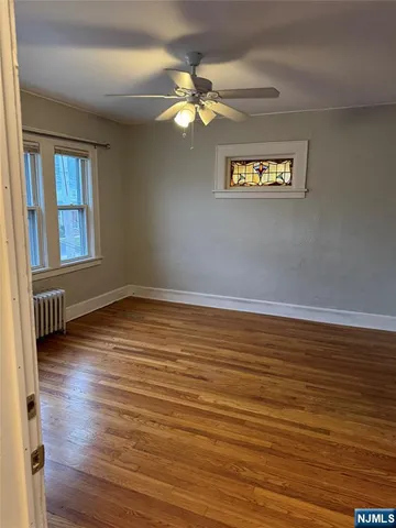 a view of a room with wooden floor and a ceiling fan