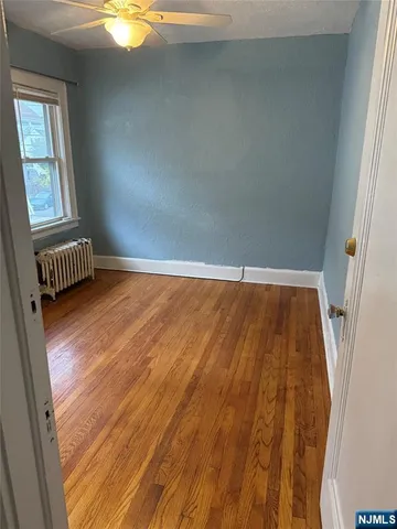 en empty room with wooden floor and fan