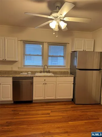 a kitchen with stainless steel appliances granite countertop a refrigerator a sink dishwasher a stove with white cabinets and wooden floor