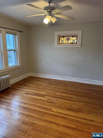 a view of an empty room with window and wooden floor
