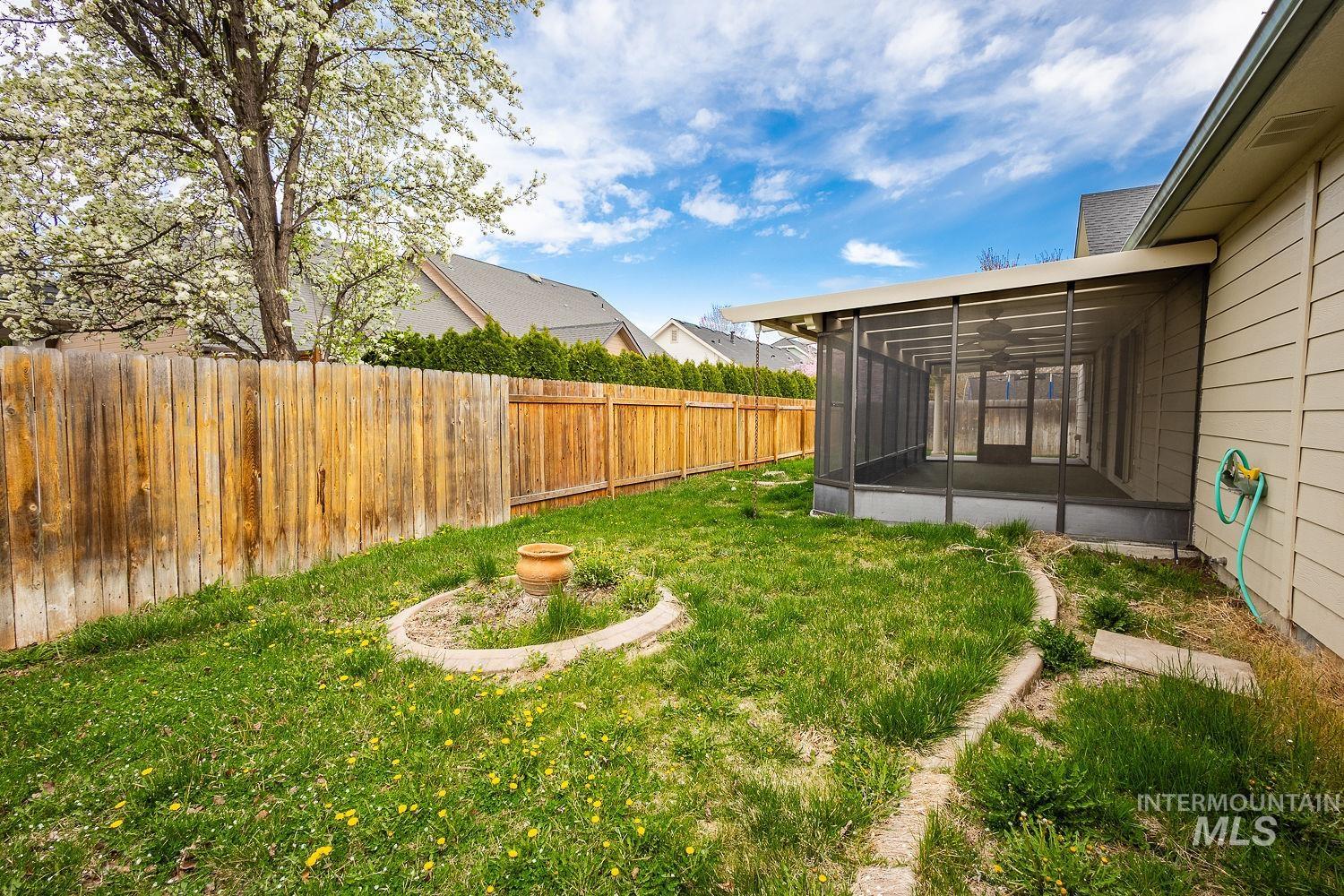 4227 North Rhodes Avenue Meridian, ID 83646 - Photo 27 of 27 Expansive backyard featuring a screened-in patio, wood privacy fencing, and a mature flowering tree