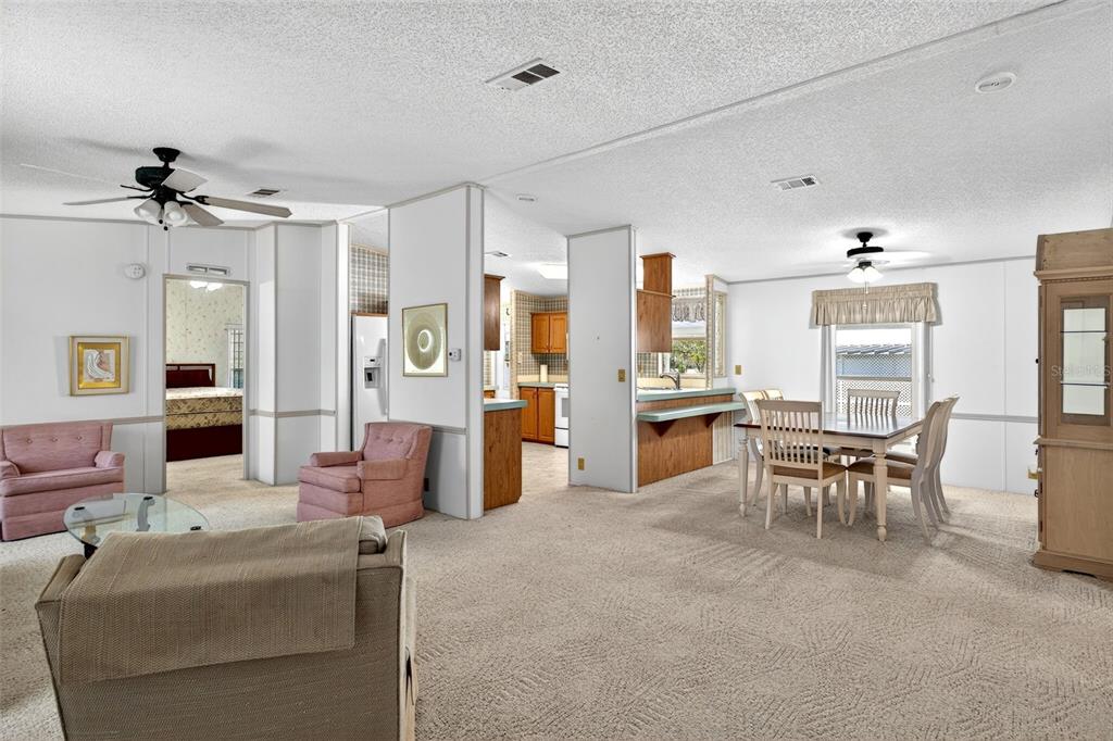 8046 Highpoint Boulevard Brooksville, FL 34613 - Photo 6 of 47 a living room with furniture a chandelier and kitchen view