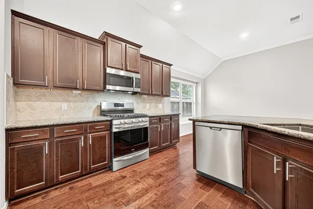 a kitchen with granite countertop wooden cabinets and stainless steel appliances
