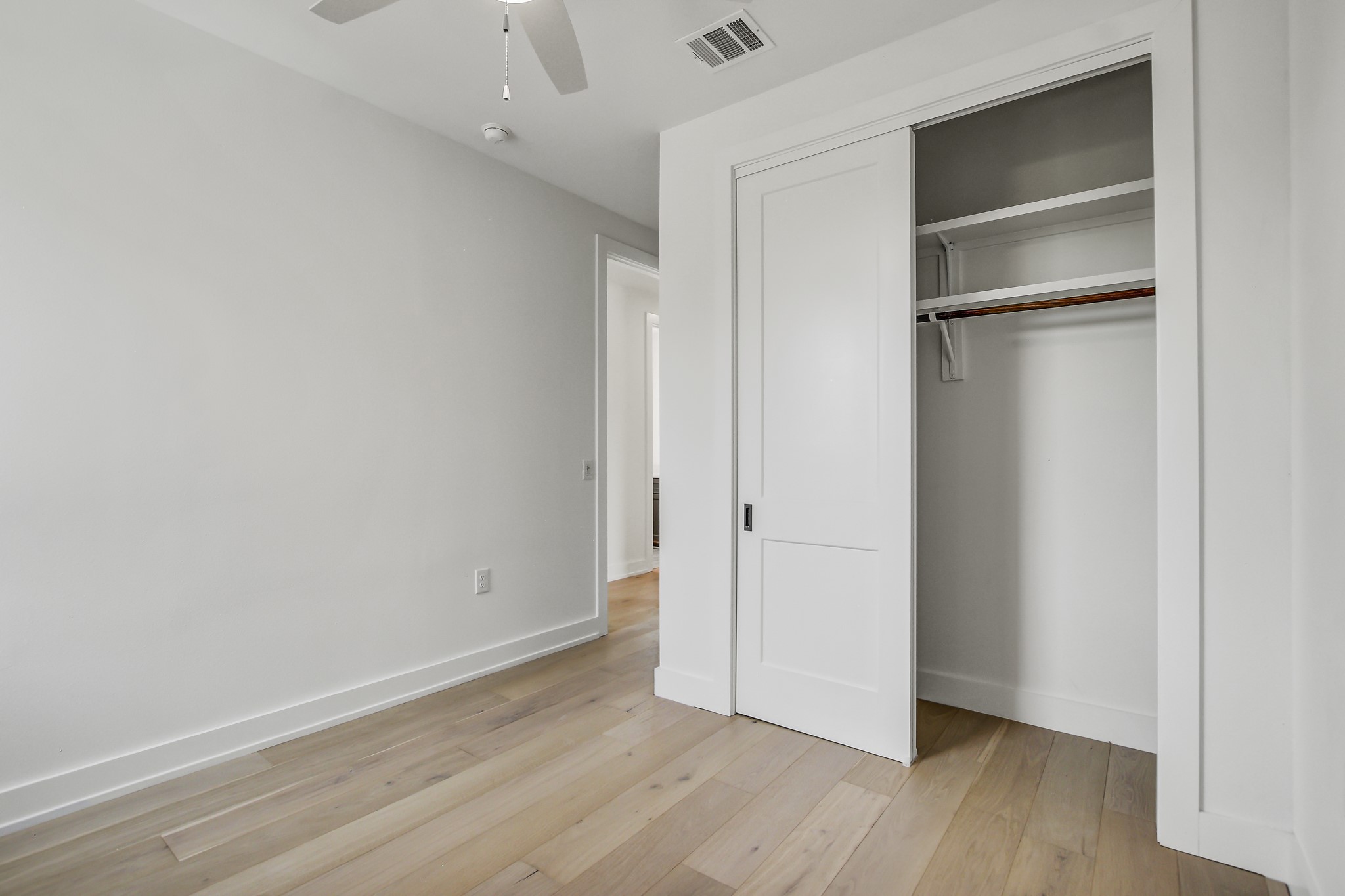 4127 East 12th Street, Unit 3 Austin, TX 78721 - Photo 19 of 29 Unfurnished bedroom with baseboards, a closet, light wood-style flooring, and a ceiling fan