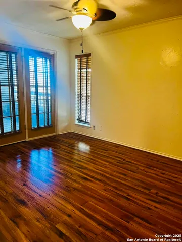 a view of empty room with wooden floor and fan