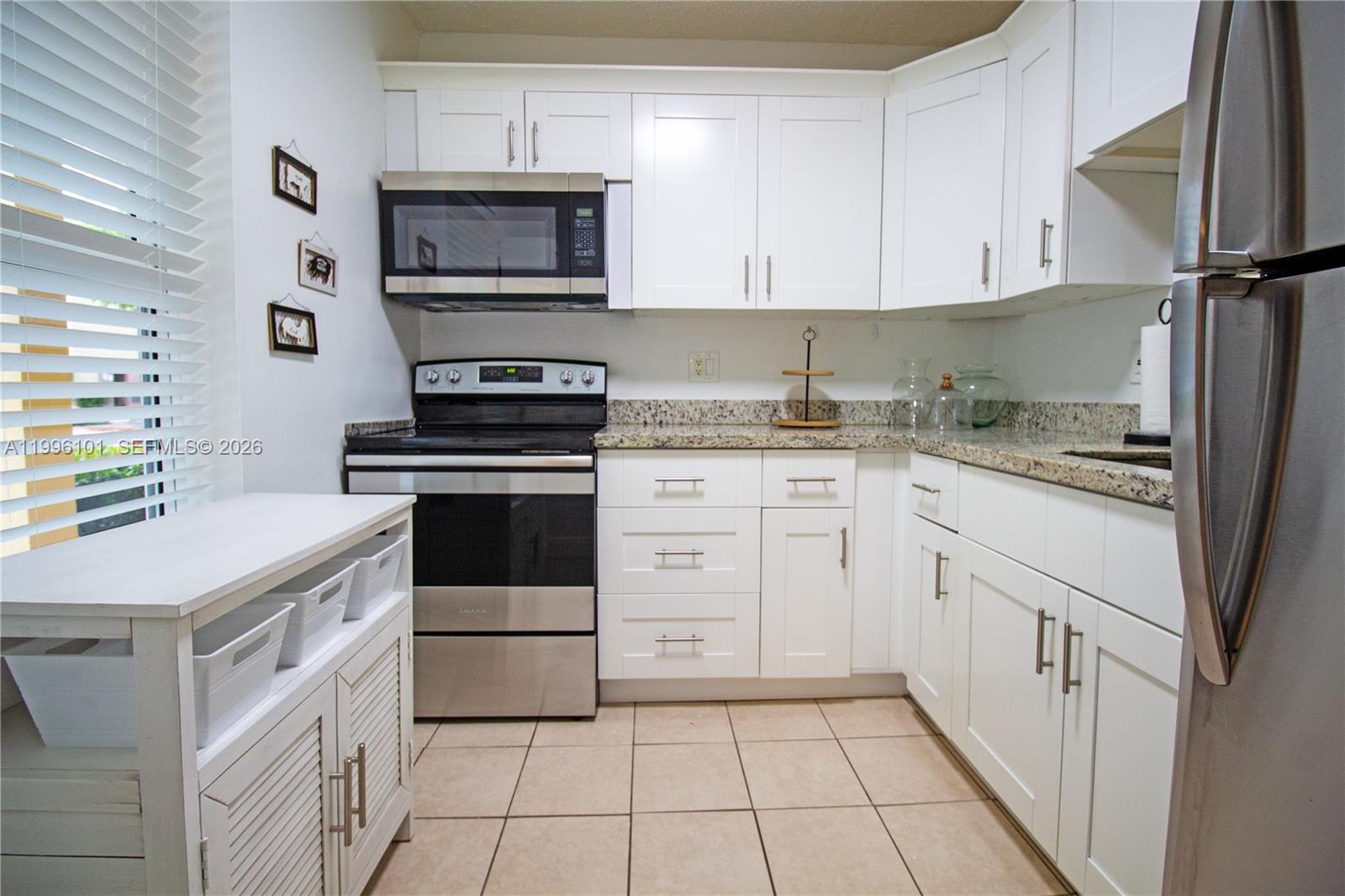 6020 Northwest 64th Avenue, Unit 108 Tamarac, FL 33319 - Photo 6 of 19 a kitchen with a stove and a microwave