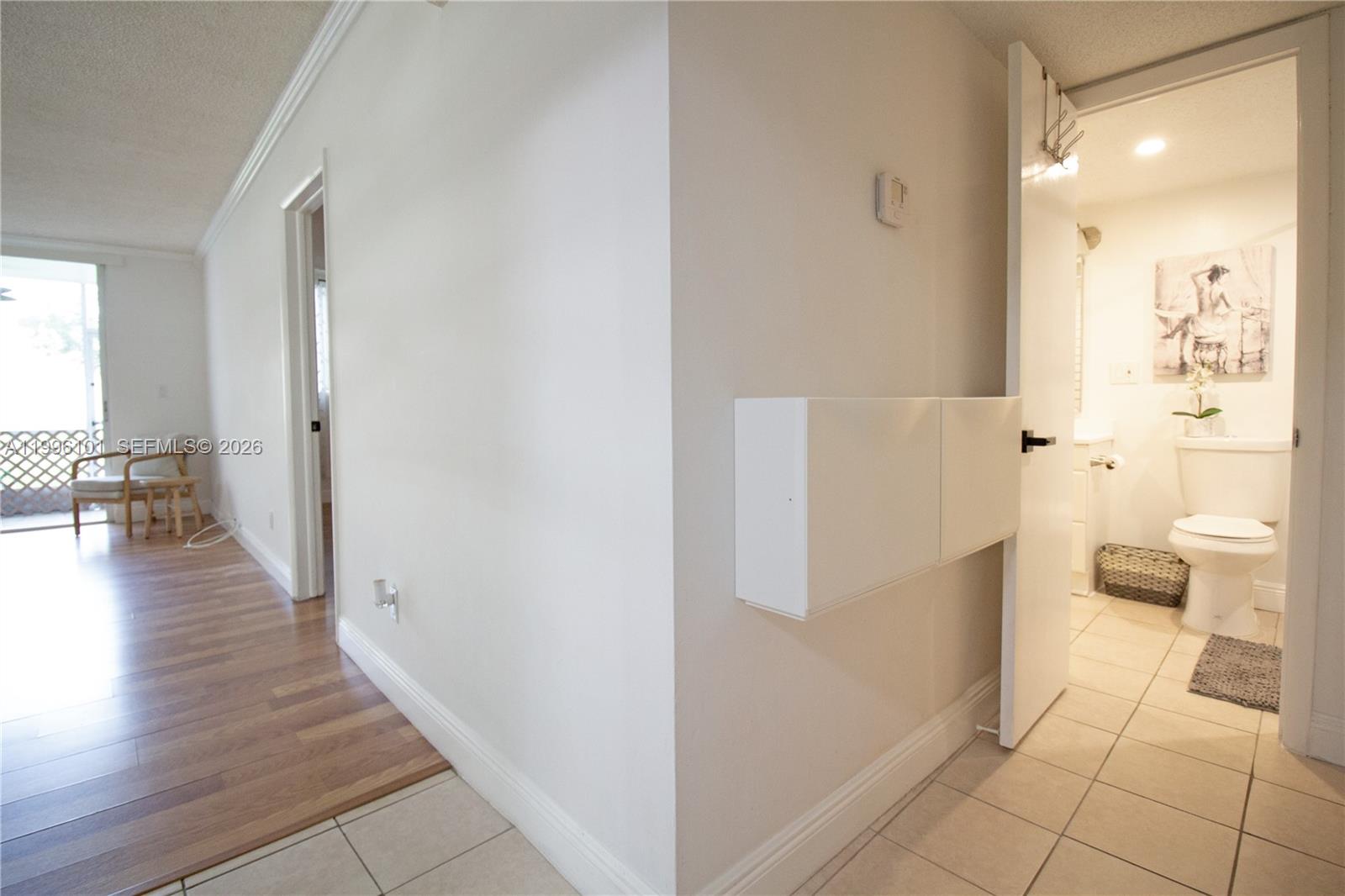 6020 Northwest 64th Avenue, Unit 108 Tamarac, FL 33319 - Photo 9 of 19 a view of a hallway with wooden floor and a bathroom