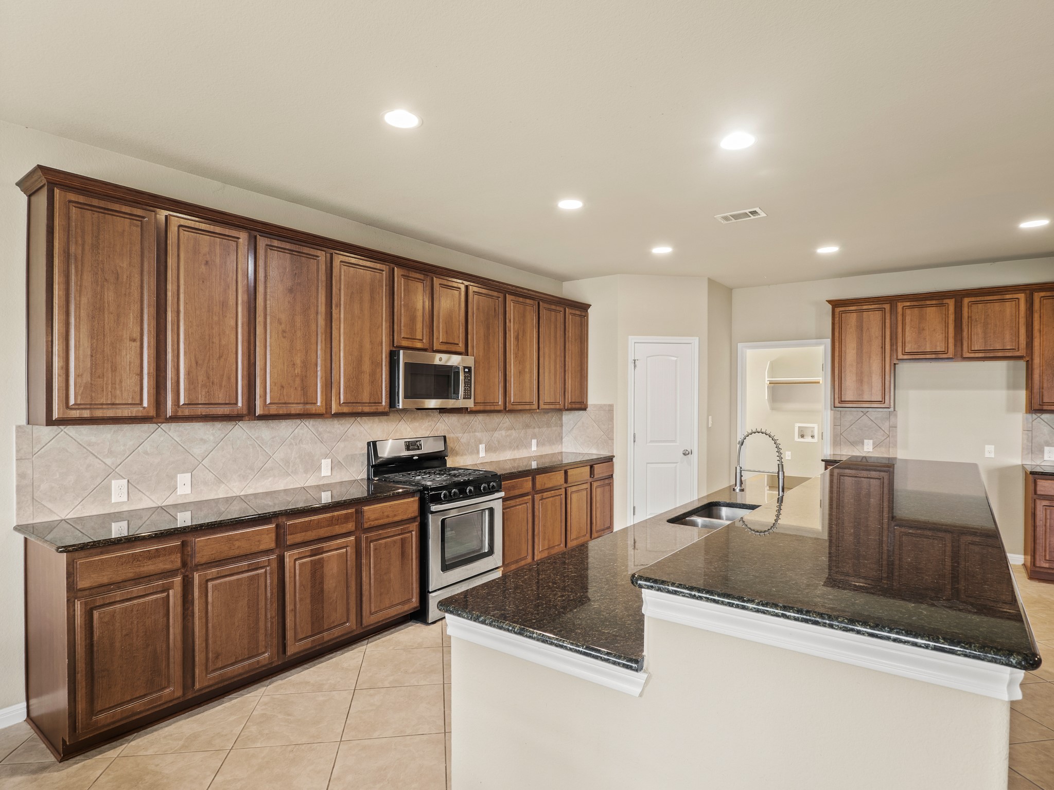17805 Silent Harbor Loop Pflugerville, TX 78660 - Photo 8 of 34 a kitchen with stainless steel appliances granite countertop a sink stove and cabinets