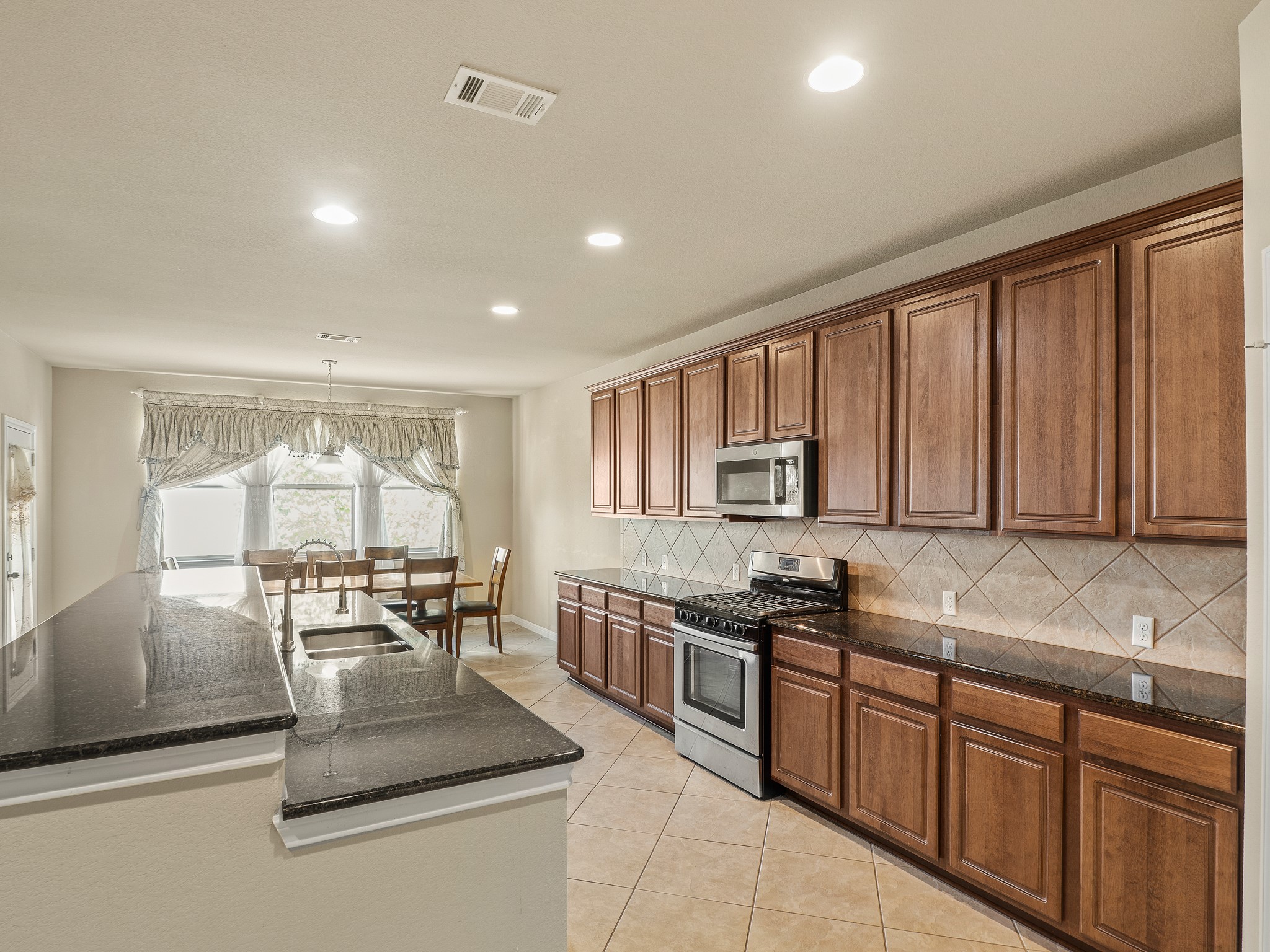 17805 Silent Harbor Loop Pflugerville, TX 78660 - Photo 10 of 34 a kitchen with stainless steel appliances granite countertop a stove a sink and a microwave