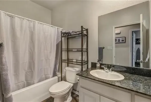 a bathroom with a granite countertop sink toilet and a mirror