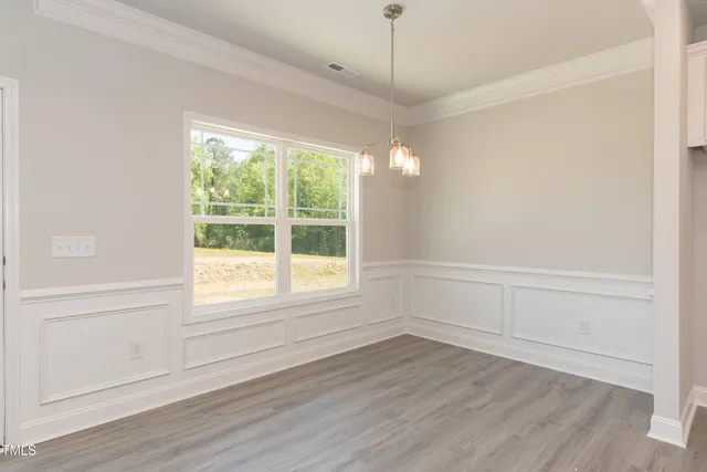 an empty room with wooden floor fireplace and windows