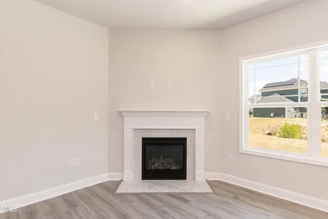 an empty room with wooden floor fireplace and windows