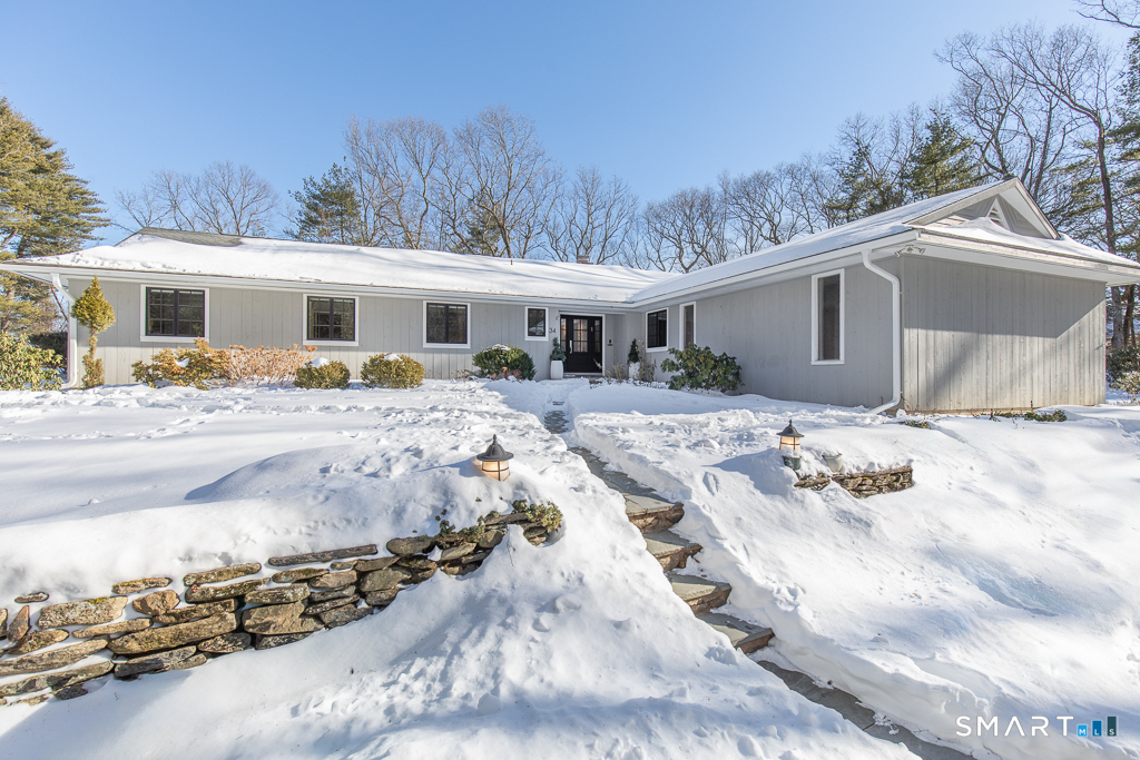 From the circular driveway, there is a stone wall along one side of the driveway and a blue stone walkway to the front door.