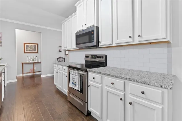 a kitchen with granite countertop white cabinets and stainless steel appliances