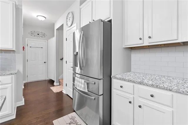 a kitchen with stainless steel appliances granite countertop a refrigerator and white cabinets