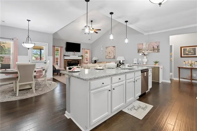 a open kitchen with stainless steel appliances granite countertop a stove a sink dishwasher a dining table and chairs with wooden floor