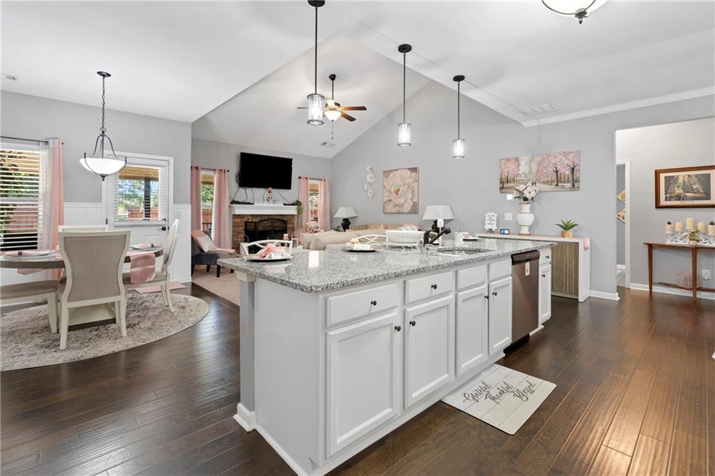 420 Andrew Ridge Drive Jefferson, GA 30549 - Photo 5 of 26 a open kitchen with stainless steel appliances granite countertop a stove a sink dishwasher a dining table and chairs with wooden floor