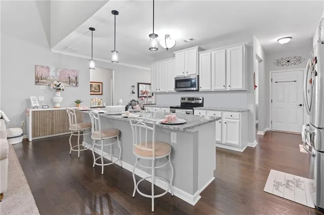 a kitchen with kitchen island granite countertop a white cabinets and chairs
