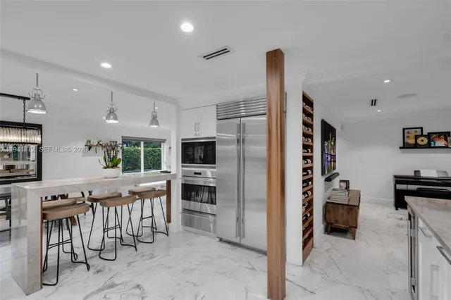 a kitchen with stainless steel appliances kitchen island granite countertop a refrigerator and a stove top oven