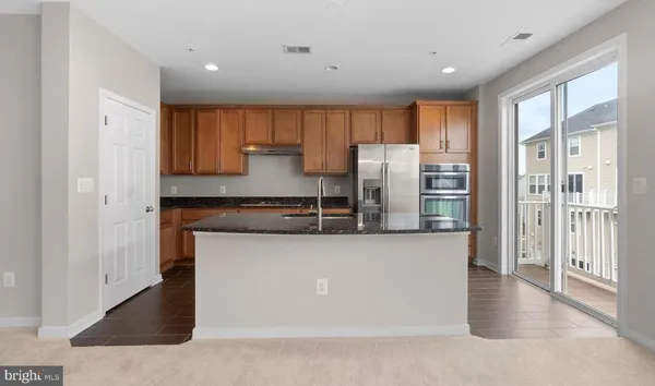 a kitchen with stainless steel appliances granite countertop a refrigerator a stove and a sink with wooden floor