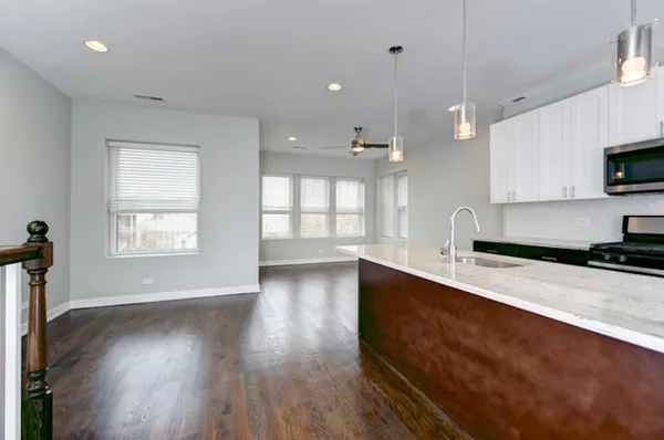 a large kitchen with stainless steel appliances a large counter top a stove a sink and a window