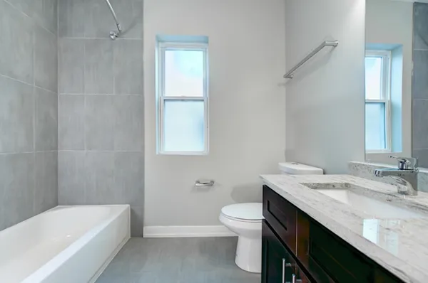 a bathroom with a granite countertop sink a toilet and bathtub