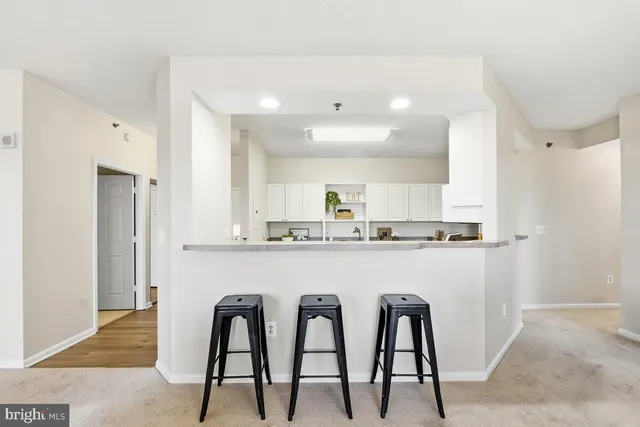 a kitchen with stainless steel appliances granite countertop white cabinets and chair